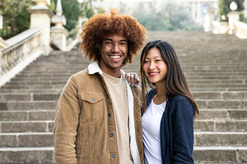 Lovely multiracial couple looking at camera in a park.Two happy diverse young persons smiling and...