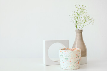 Gypsophila flowers and candle on table near light wall in room, closeup