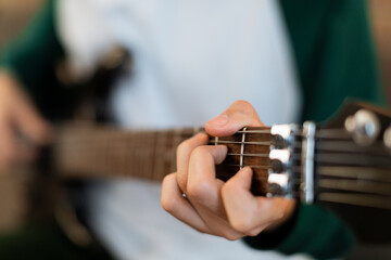 Closeup of Teen Boy's Hands Learning Chords on Guitar Indoors