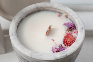 Holder with candle and flowers on table in room, closeup