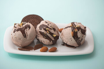 Chocolate ice cream in balls decorated with nuts and chocolate icing, blue background. Summer cooling desserts, cafe menu