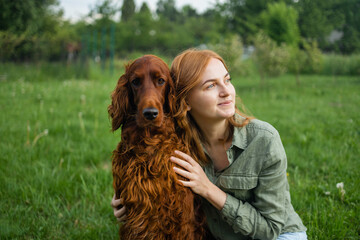 Beautiful woman hugging and kissing Irish Setter dog. Dog and owner together outdoors. Love and...