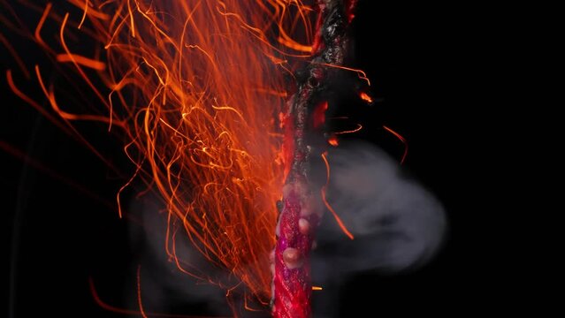 A macro shot of a burning fuse in front of a black background.