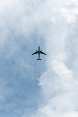 Avión en el cielo azul con nubes desde abajo, avión de pasajeros de alto vuelo. 