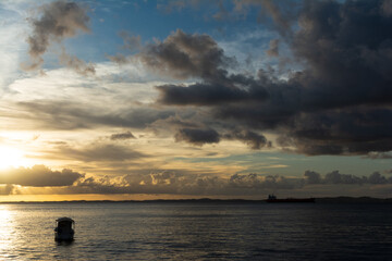 Silhouette of a boat against the dramatic sunset under the sea.