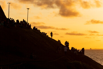 Silhouette of people and mountain against sunset.