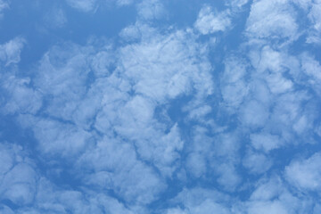 Blue sky with clouds. Spring or summer background. 
White clouds on the blue sky have a complex pattern.
