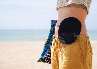 an unrecognizable woman with a ostomy bag looking at the beach with a self esteem. Digestive cancer