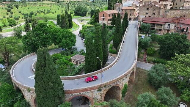 Auto d'epoca sul ponte storico di San Quirico D&rsquo;Orcia in Toscana.
Vista aerea della citt&agrave; e delle auto storiche.