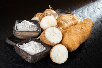 pile of cassava and cassava flour on dark background (Manihot esculenta)