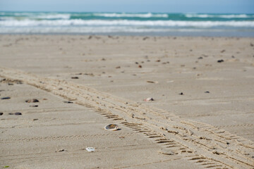 Tire tracks and footprints on the sand at the beach on a sunny day in Denmark, North Sea. Traces of car tires footprints in the sand