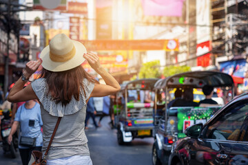 A tourist woman on a sightseeing tour walks down the famous Yaowarat street in Chinatown, Bangkok,...