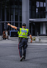 Police man is directing traffic during the rush hour in down town Toronto. Police man regulating...