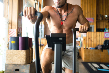 Naklejka premium Man using an air bike on a gym