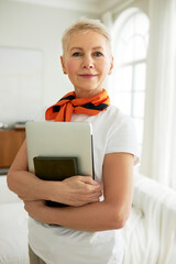Vertical image of confident pretty charming positive senior teacher with stylish haircut standing...