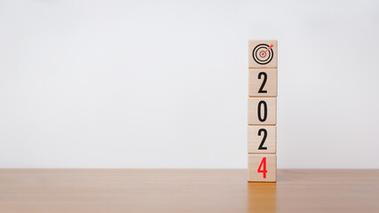 Wood cube block with 2024 text and arrow icon on wooden table with white background. New year goal,...