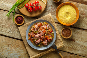 Israeli couscous in spices with sumac and chicken pieces on a linen napkin next to the ingredients.