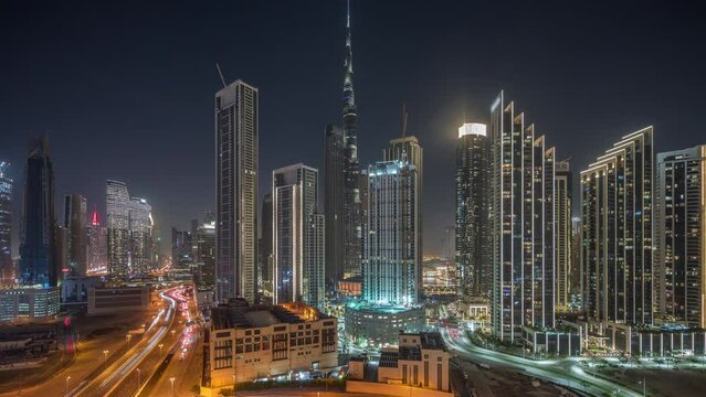 Aerial view of Dubai Downtown skyline surrounded by many illuminated towers night timelapse. Business area in smart urban city. Skyscraper and high-rise buildings from above, UAE.