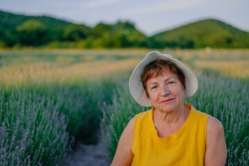 close-up portrait of an elderly woman in summer in a yellow dress and hat in a lavender field