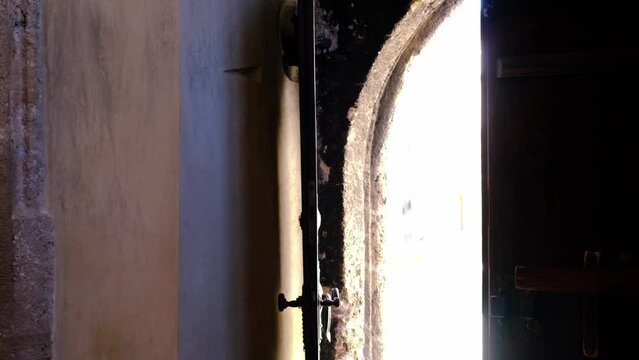 old heavy wooden door mystically closes and opens by itself, mysterious light in doorway floods portal, invisible ghost in an old building, architecture background, halloween horrors