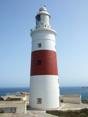 Fototapeta na wymiar Red and white lighthouse on Spanish Atlantic coast with sea view and some ships in background