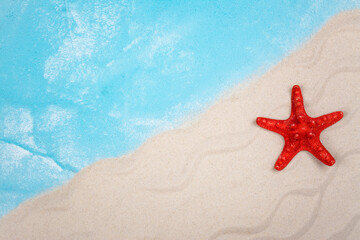Fototapeta na wymiar Red starfish on sandy beach. Summer background. Top view. Copy space