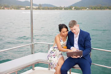 businessman using laptop computer and talking with his partner on luxury yacht