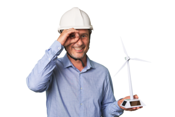 A middle-aged architect man holding a windmill model excited keeping ok gesture on eye.