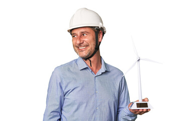 A middle-aged architect man holding a windmill model looks aside smiling, cheerful and pleasant.