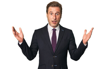 A middle-aged businessman isolated receiving a pleasant surprise, excited and raising hands.