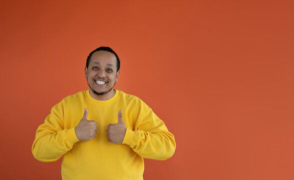 Portrait Of A Positive Young Black Man Smiling Happily, Showing White Teeth, Looking Forward And Showing Thumbs Up