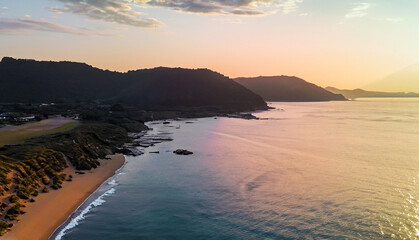 Fototapeta premium aerial beautiful shot of a seashore with hills on the background at sunset