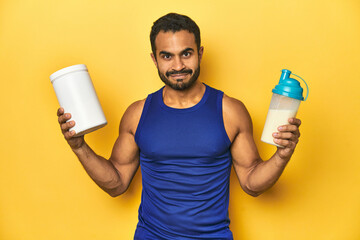 Fit Latino man with protein shake and supplement, supporting sports nutrition.