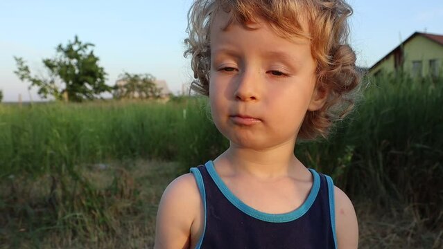 A little white boy with curly hair eats red currants from his father's hand, his reaction is priceless
