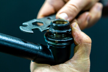 Repair of a road bike on a black background. A bicycle mechanic repairs the steering column. Black bicycle frame in the workshop.