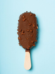 Chocolate and almonds stick ice cream isolated on cyan background, with condensation