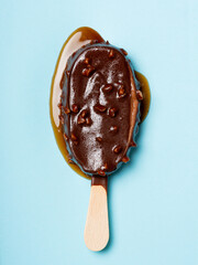Melted chocolate and almonds stick ice cream isolated on cyan background