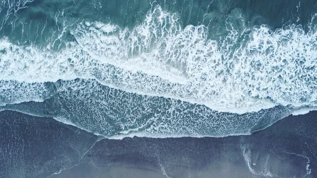 4K UHD aerial drone view of waves crashing on beach from above. 