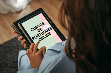 A woman holds a tablet in her hands on the screen of which it is written - Online Portuguese courses