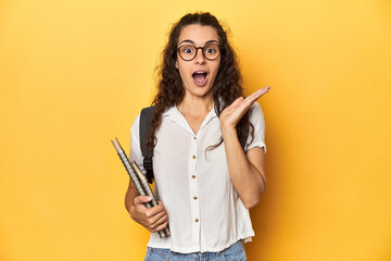 Fototapeta premium Student holding notebooks, glasses, backpack on, surprised and shocked.