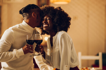 African american couple having romantic date at home while drinking wine and kissing