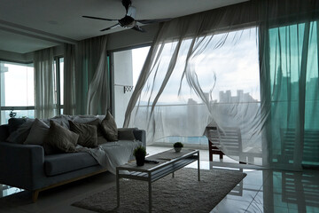 The wind rustles the curtain of the panoramic window with a cityscape