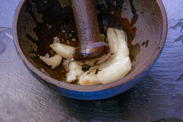 Metal mortar with crushed garlic and oil in the kitchen.1