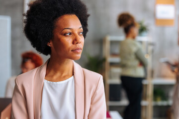 Portrait of elegant African-American business woman in busy startup office.