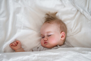 Cute caucasian child toddler sleeps on white sheets