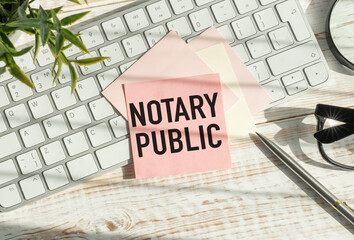 NOTARY PUBLIC text on a sticky on sticky on Keyboard with pen on wooden background.