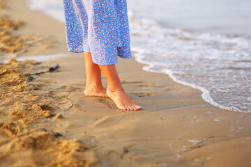 Close up of woman feet walking barefoot on sand beach in sea water. Vacation, travel and freedom...