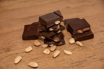 Close-up of delicious pieces of dark chocolate with almonds on a wooden table.