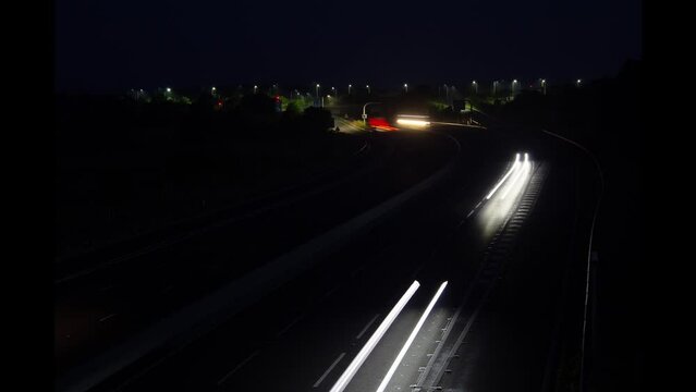 long pattern of lights on UK road at night trailing timelapse