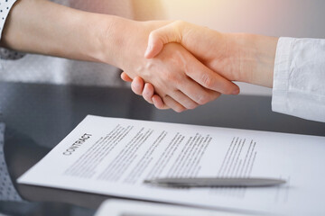 Business people signing contract papers while sitting at the glass table in office, closeup. Partners or lawyers working together at meeting. Teamwork, partnership, success concept